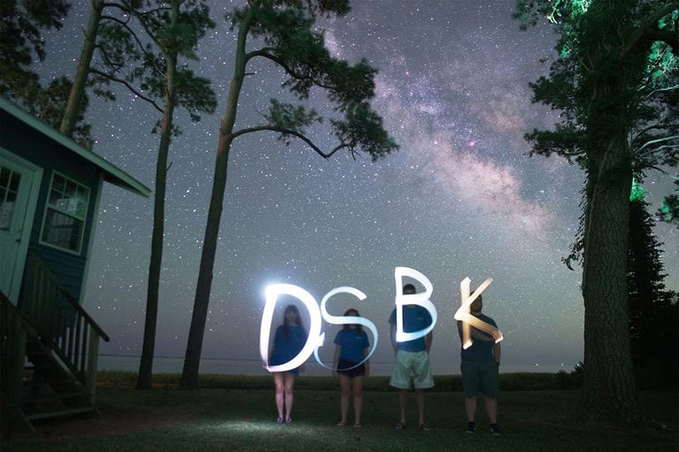 Stargazers under the Milky Way, spelling out DSBK with light trails