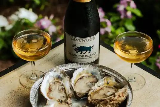 Oysters on ice with glasses of sparkling wine and a bottle of Eastwood Blanc de Blancs
