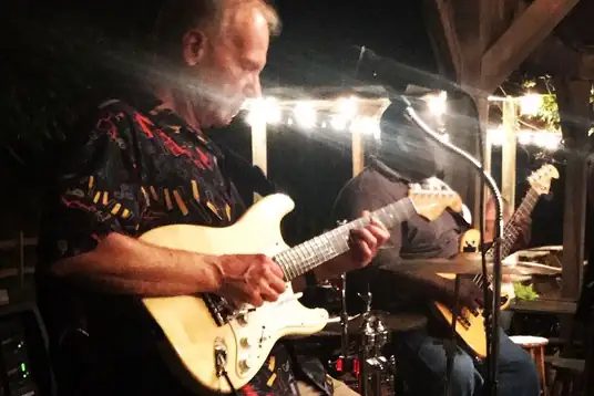 Chickenhead Blues guitarist performing under string lights
