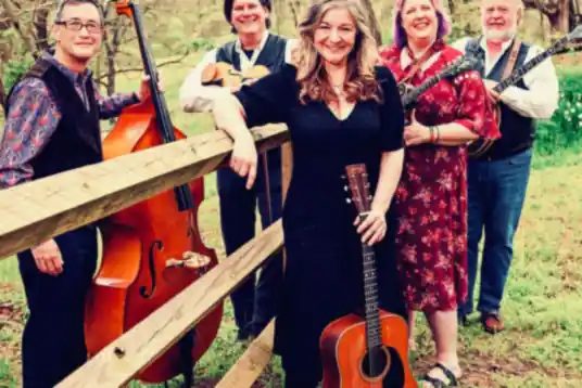 Valerie Smith and Liberty Pike with bass, guitars and fiddle by a split-rail fence